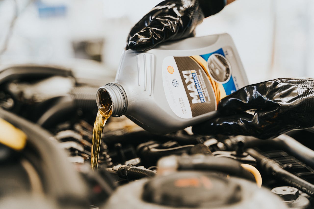 contact-img Close-up of a mechanic pouring engine oil into a car engine, highlighting maintenance work.