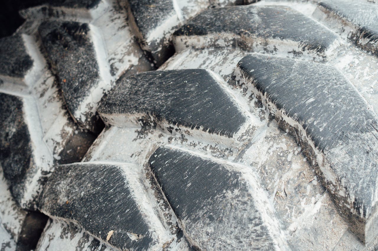 Detailed view of a worn tractor tire showing its deep tread pattern and grooves.