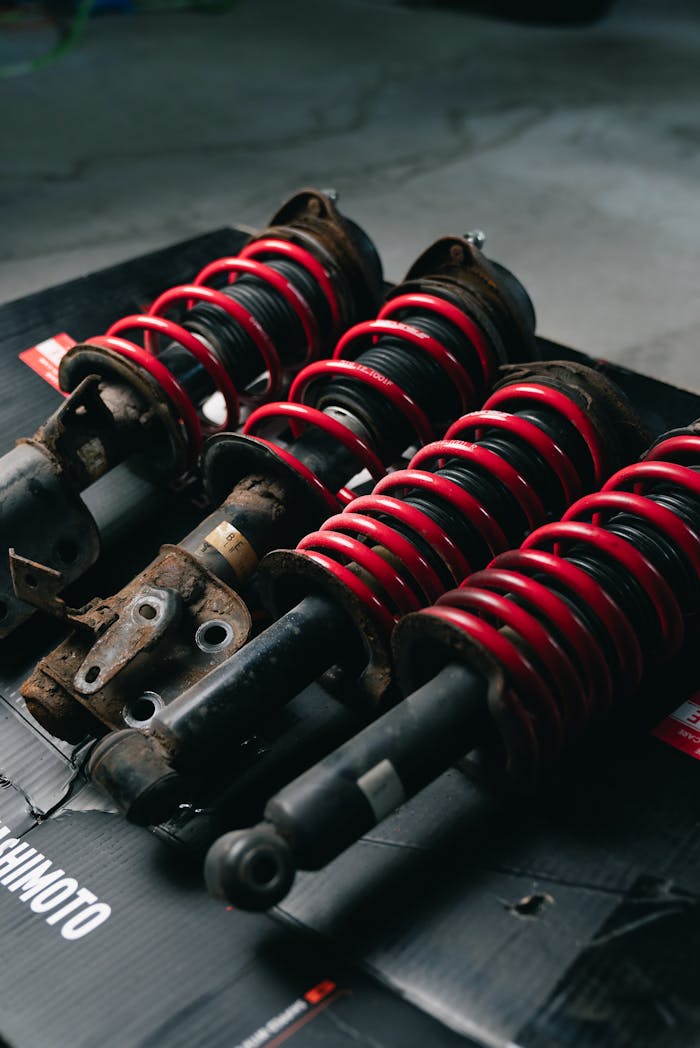 Close-up image of red coilover suspensions with a black background, ideal for automotive or mechanical themes.
